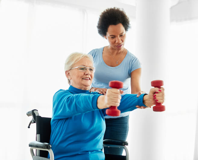 A female community support worker assisting an elderly female client with exercises