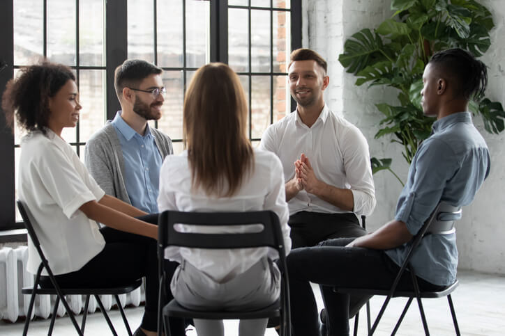 A male community support worker in a group discussion with clients