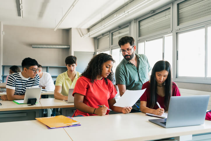 A career college professor interacting with a student during a class
