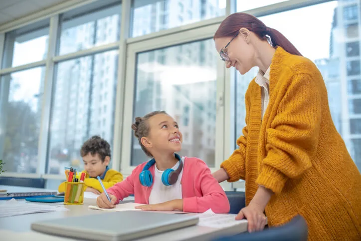 An education assistant supporting a student during class activities