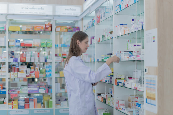 A pharmacy assistant organizing medication inventory in a retail pharmacy