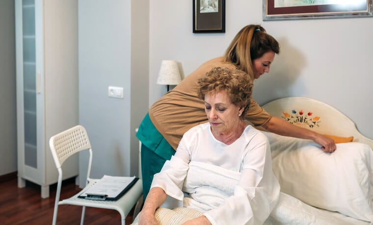 A support worker helping a senior in a care facility