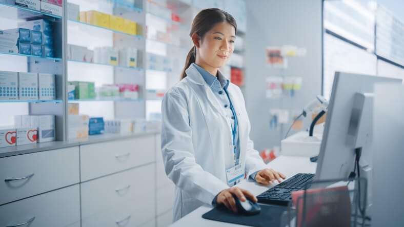 A hospital pharmacy assistant reviewing medication inventory demonstrates essential skills for pharmacy assistants