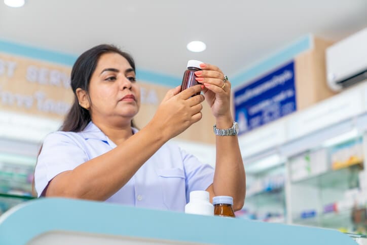 A hospital pharmacy assistant preparing medication in a clinical pharmacy setting