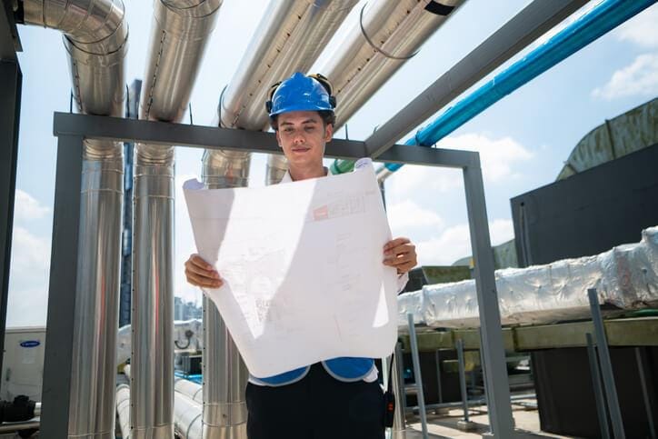 An engineering drafting student reviewing industrial piping layouts