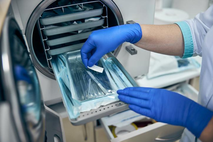 A technician loading sterilized medical instruments into an autoclave