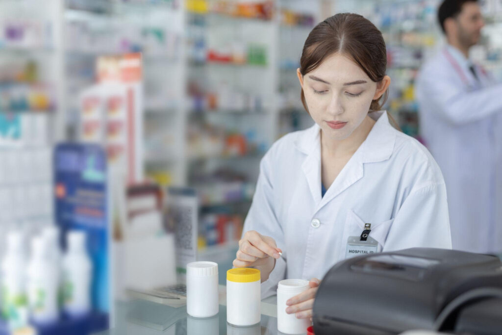 A pharmacy assistant preparing prescription labels for pharmacist verification